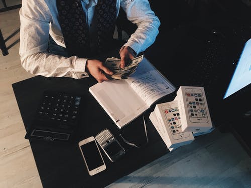 Man working with cash in his hand next to a calculator and books
