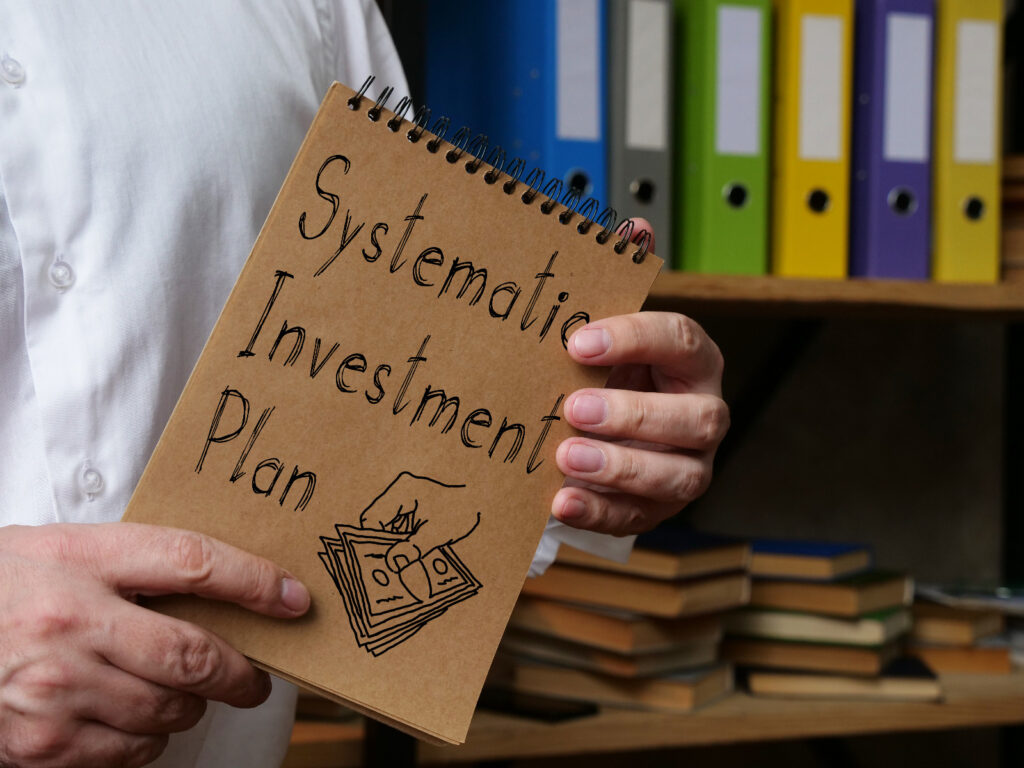 A person holding a notepad with Systematic Investment Plan written on it